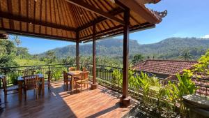 una terraza de madera con mesa y sillas en la cima de una montaña en Puri Jumpungan Villas en Sidemen