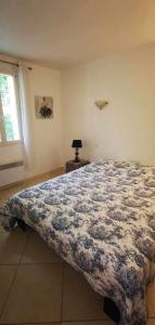 a bedroom with a bed with a blue and white blanket at Villa les chênes in Bargemon