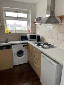 a kitchen with a stove and a washing machine at Charming 2-Bed Apartment in Heathrow first floor in Hayes