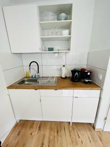 a kitchen with white cabinets and a sink at NaSa Wohnen Zentrum in Krefeld