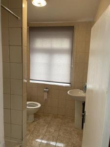 a bathroom with a toilet and a sink and a window at Charming 2-Bed Apartment in Heathrow first floor in Hayes