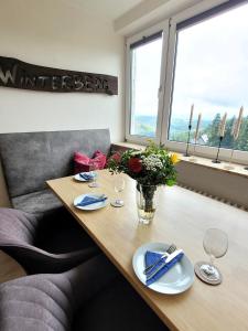 ein Esszimmer mit einem Tisch mit Gläsern und Blumen in der Unterkunft Winterberg Appartement 21093 in Winterberg