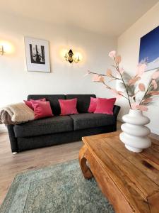 ein Wohnzimmer mit einem schwarzen Sofa und rosa Kissen in der Unterkunft Winterberg Appartement 21093 in Winterberg