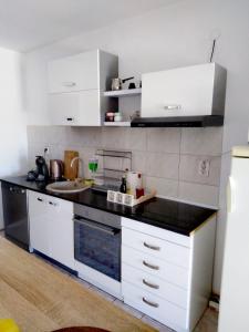 une cuisine avec des placards blancs et un comptoir noir dans l'établissement Banin, à Skradin