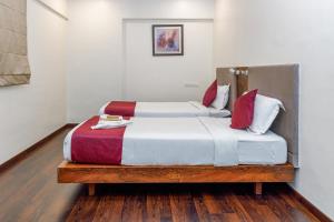 a bedroom with two beds with white and red pillows at J Hotel and Banquets in Mumbai