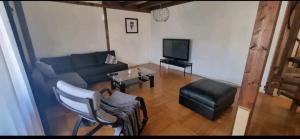 a living room with a couch and a tv at Villa avec grand jardin, proche du centre-ville in Yverdon-les-Bains