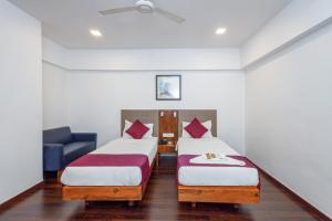 a hotel room with two beds and a blue chair at J Hotel and Banquets in Mumbai