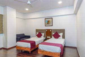 a hotel room with two beds and a chair at J Hotel and Banquets in Mumbai