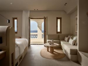 a living room with a couch and a bed and a table at Domes Noruz Mykonos in Mikonos