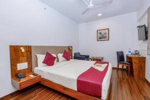 a bedroom with a bed and a desk and chairs at J Hotel and Banquets in Mumbai