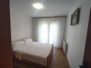 a bedroom with a white bed and a window at Apartman Bor s velikom terasom idealan za boravak s obitelji in Livno