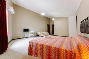 um quarto com uma cama grande e um cobertor laranja em La foresteria di Mony e Ale em Carbonia