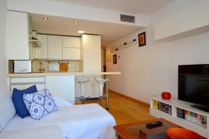 uma sala de estar com uma cama branca e uma cozinha em Coqueto apartamento a pocos metros de playa em Can Pastilla