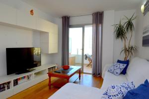 un soggiorno con divano bianco e TV di Coqueto apartamento a pocos metros de playa a Can Pastilla