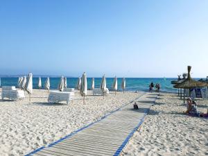 einen Strand mit weißen Sonnenschirmen und Stühlen sowie das Meer in der Unterkunft Apartamento delante del mar in Can Pastilla