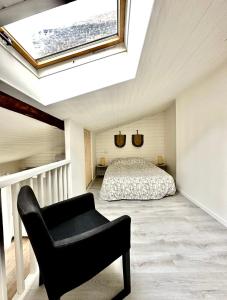 een slaapkamer met een bed en een stoel en een dakraam bij C La reserve - St ROSE Ethnique in Clermont-Ferrand