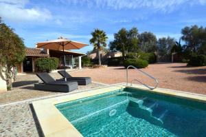 a swimming pool with two chairs and an umbrella at Casa con piscina en bonito entorno Mia in Costitx