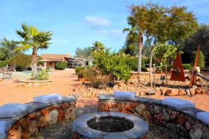 a stone fire pit in a yard with palm trees at Casa con piscina en bonito entorno Mia in Costitx