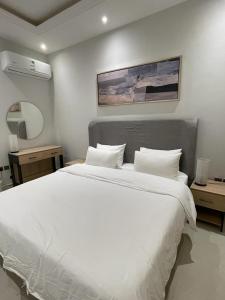 um quarto com uma grande cama branca e duas mesas em شقة نيرفانا ريزدنس Nirvana Residence Apt em Riyadh