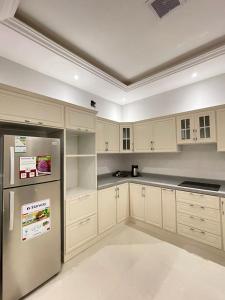 uma cozinha com armários brancos e um frigorífico de aço inoxidável em شقة نيرفانا ريزدنس Nirvana Residence Apt em Riyadh