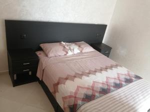um quarto com uma cama e duas mesas de cabeceira em Perla Andaloussia em Minaret de Mansuria