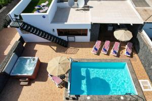 an overhead view of a swimming pool with chairs and umbrellas at Villa Aurelia - Pool, Jacuzzi, BBQ and Ping-Pong By Lanzarote Vacation Homes in Playa Blanca