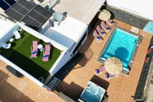 an overhead view of a pool with lawn chairs and solar panels at Villa Aurelia - Pool, Jacuzzi, BBQ and Ping-Pong By Lanzarote Vacation Homes in Playa Blanca +45 photos