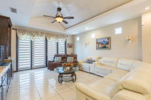 a living room with white furniture and a ceiling fan at Tranquility in the Cudlesac in McAllen