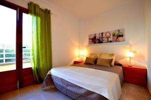 - une chambre avec un lit doté de rideaux verts et d'une fenêtre dans l'établissement Apartamento en Alcudia a 100 metros de la playa, à Alcúdia