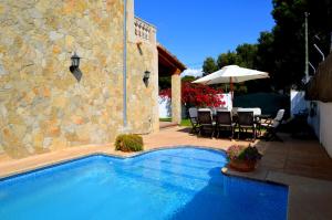 a swimming pool next to a building with a table and chairs at Bonito chalet con piscina cerca del mar in Can Pastilla