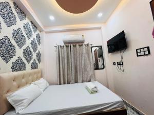 a small bedroom with a bed and a tv at The Bella Guesthouse in Varanasi