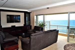 a living room with a couch and a television and a balcony at 26 Bronze Bay Umhlanga Rocks in Durban