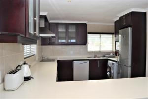 a kitchen with brown cabinets and a white refrigerator at 26 Bronze Bay Umhlanga Rocks in Durban