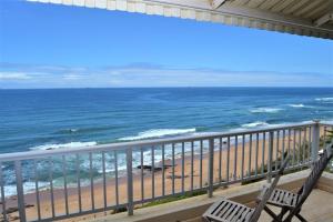 two chairs sitting on a balcony looking at the beach at 26 Bronze Bay Umhlanga Rocks in Durban