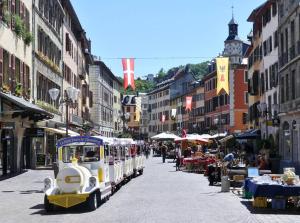 un tramway descendant une rue urbaine avec des bâtiments dans l'établissement L'instant léger - Centre ville, à Chambéry