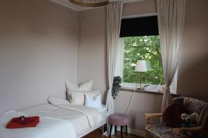 CosyPlace; close to beach, nature, train, grocery في Köpingebro: غرفة نوم بسرير ونافذة وكرسي