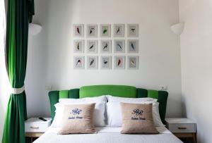 a bed with a green headboard and some pictures on the wall at Residenza Romana in Rome