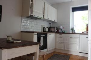 a kitchen with white cabinets and a wooden table at CosyPlace; close to beach, nature, train, grocery in Köpingebro