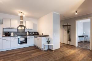 uma cozinha com armários brancos e uma mesa num quarto em Living Neuburg em Neuburg an der Donau