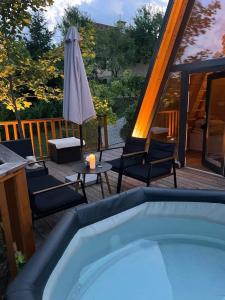 uma banheira de hidromassagem num deque com cadeiras e um guarda-sol em Glamping Holiday House with hot tub and sauna- Hisa oddiha em Smarjeske Toplice