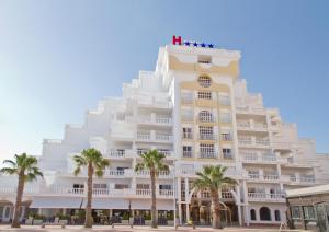 un grand bâtiment blanc avec des palmiers devant lui dans l'établissement Hotel Los Delfines, à La Manga del Mar Meno