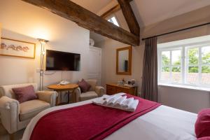 a bedroom with a bed and chairs and a tv at The Old Coach House in Ripon