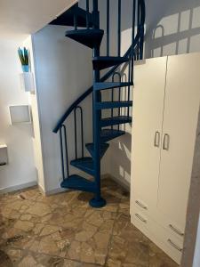 un escalier en colimaçon bleu dans une pièce à côté d'une armoire dans l'établissement La casa di Ginevra, à Polignano a Mare
