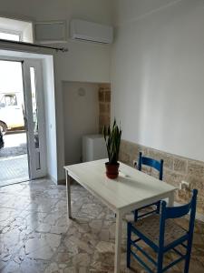 une table blanche avec deux chaises et une plante en pot dans l'établissement La casa di Ginevra, à Polignano a Mare