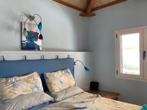 1 dormitorio con 1 cama con cabecero azul y ventana en VILLA AZUL, en Centro histórico de Alónnisos