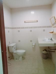 a white bathroom with a toilet and a sink at Kingfisher House and Bar in Pattaya South