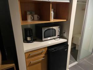 una pequeña cocina con microondas y nevera. en ~Four-star serviced apartment en Honolulu