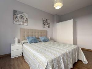 una camera da letto con un grande letto con cuscini blu di Paxarinos Playa by FlowHome a Gijón