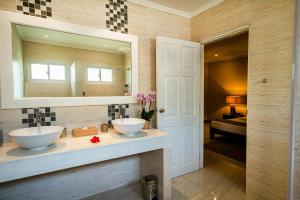 a bathroom with two sinks and a mirror at Anse Boudin Chalets & Villa in Anse Possession