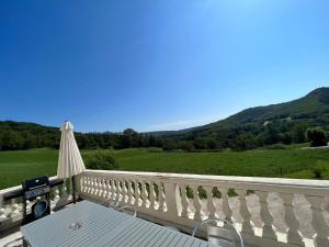 - un balcon blanc avec une table et un parasol dans l'établissement Trois gîtes ensemble dans le même immeuble devant la piscine avec terrasses offrant une vue magnifique, dont une couverte au niveau de la piscine et vue sur la vallée à l'étage, 